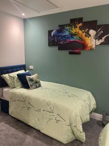 a bed in a room with three paintings on the wall at The Ivy in Marston Green