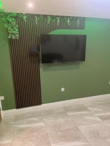 a flat screen tv hanging on a green wall at The Ivy in Marston Green