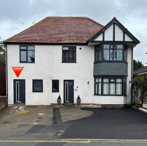 a white house with a red triangle on it at The Ivy in Marston Green