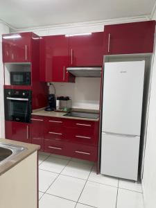 a kitchen with red cabinets and a white refrigerator at Appartement 3 chambres récemment rénové in Les Abymes +2 photos