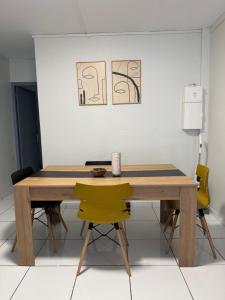 a wooden table with yellow chairs in a room at Appartement 3 chambres récemment rénové in Les Abymes