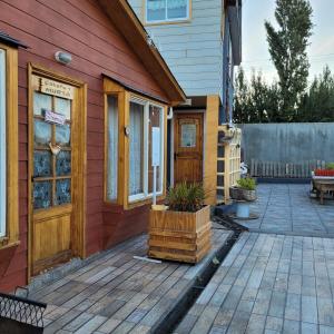 a red house with a wooden door and a patio at CABAÑAS RINCON SOLEADO, Chile Chico in Chile Chico