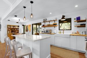 a kitchen with white cabinets and a large island at Red Bird Cottage in Wimberley