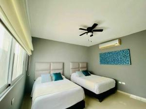 a bedroom with two beds and a ceiling fan at Grand Blue Playa in Playa del Carmen +36 photos