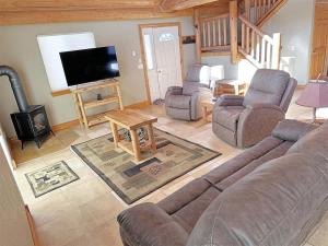 a living room with a couch and chairs and a flat screen tv at Cottage at Storm Mountain #3 in Hill City