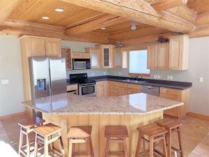 a kitchen with a counter with stools and a refrigerator at Cottage at Storm Mountain #3 in Hill City