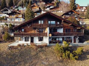 a large wooden house on a hill with houses at Gemütliche Ferienwohnung in Ladir bei Flims Laax in Ilanz