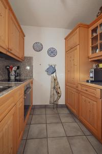 a kitchen with wooden cabinets and a tile floor at Gemütliche Ferienwohnung in Ladir bei Flims Laax in Ilanz