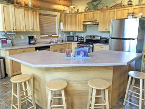 a kitchen with a large island with stools in it at Cottage at Storm Mountain #5 in Hill City