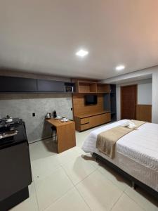 a bedroom with a bed and a desk and a kitchen at Uruguaiana House in Uruguaiana