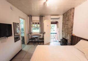 a bedroom with a bed and a table in a room at Pousada Flor de Penedo in Penedo