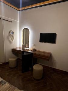 a bedroom with a desk with a television and stools at 44 Inn in Dahab