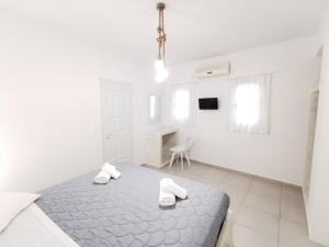 a white bedroom with a bed and a chair at Meltemi Chora Amorgos in Amorgos