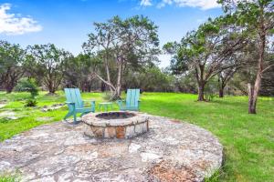 two blue chairs sitting around a fire pit in a field at Canyon Vista in Wimberley