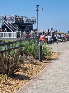 a group of people sitting on benches near a pier at BELLESVIEW Clarach Bay in Aberystwyth