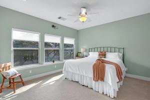a bedroom with a bed and a chair and windows at Casa Robles- The Mockingbird in Wimberley