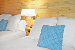 a bedroom with two beds with white pillows and a lamp at Wimberley Log Cabins Resort and Suites- Unit 8 in Wimberley