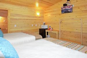 a bedroom with two beds and a desk and a tv at Wimberley Log Cabins Resort and Suites- Unit 8 in Wimberley