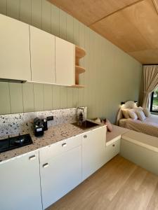 a kitchen with white cabinets and a bed in a room at The Flower Sanctuary Tiny Home in Springbrook +6 photos