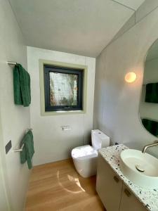 a bathroom with a white toilet and a sink at The Flower Sanctuary Tiny Home in Springbrook