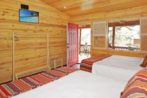 a log cabin bedroom with two beds and a tv at Wimberley Log Cabins Resort and Suites- Unit 7 in Wimberley