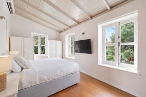 a bedroom with a bed and two windows at Pietermaai Oasis in Willemstad