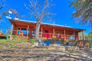 a house with red doors and chairs in front of it at Clearwater Log Home in Wimberley