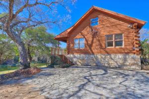 a log cabin home with a stone driveway at Clearwater Log Home in Wimberley