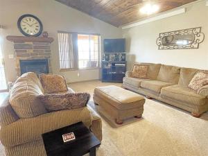 a living room with two couches and a clock on the wall at Prospector in Hill City