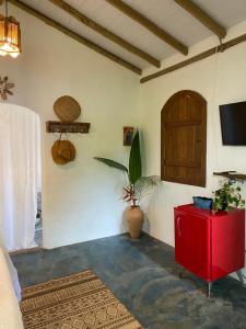 a living room with a red cabinet and a tv at Chalé Rosa in Trancoso