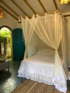 a bedroom with a bed with a canopy at Chalé Rosa in Trancoso