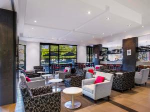 a lobby with chairs and tables and a bar at Mantra Hindmarsh Square in Adelaide