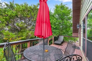 a table with a red umbrella on a balcony at Clutter Falls Retreat - Guest House in New Braunfels