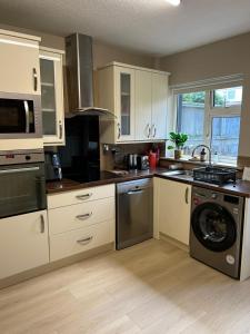 a kitchen with white cabinets and a washer and dryer at The Greenway Getaway in Abbeyside