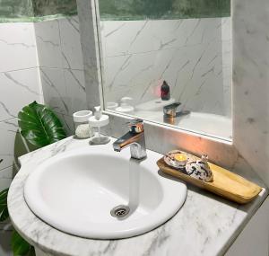 a bathroom sink with a mirror and a white counter at Riad Sor in Essaouira