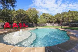 a swimming pool with red chairs and a fountain at Wimberley Log Cabins Resort and Suites- Unit 4 in Wimberley