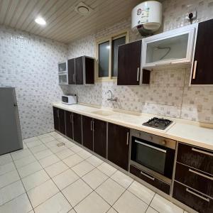 a kitchen with brown cabinets and a stove top oven at اكنان للشقق المفروشة in Buraydah +44 photos