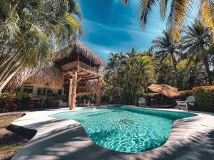 a swimming pool with a gazebo and palm trees at Candelaria 5 Moterrico in Taxisco