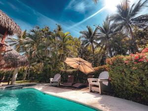 a pool with chairs and an umbrella and palm trees at Candelaria 5 Moterrico in Taxisco