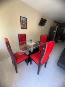 a dining room with red chairs and a glass table at Apartamentos KARS in Ríohacha +17 photos