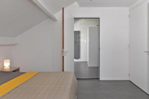 a bedroom with a bed and a door leading to a bathroom at Penthouse XL Veerse Meer in Kamperland