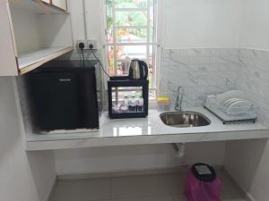 a kitchen counter with a sink and a microwave at Tiny House Anjung Batu Tangkak in Tangkak