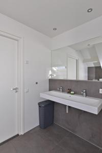 La salle de bains blanche est pourvue d'un lavabo et d'un miroir. dans l'établissement Penthouse XL Veerse Meer, à Kamperland