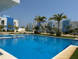 a large swimming pool with palm trees and buildings at La casa Azul in Acapulco