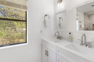 a white bathroom with two sinks and a window at Wimberley Log Cabins Resort and Suites- Unit 2 in Wimberley