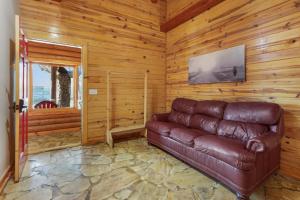a living room with a leather couch in a room with wooden walls at Wimberley Log Cabins Resort and Suites- Unit 2 in Wimberley +13 photos