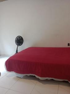 a bedroom with a red bed and a fan at Renascer in São Pedro da Aldeia
