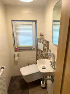 a bathroom with a sink and a toilet and a mirror at Modernes Reihenhaus mit Terrasse drei Schlafzimmer fuer sechs Personen in Kempten +7 photos