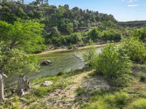 a river in the middle of a field with trees at Rio Cantando in Wimberley