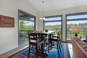 a dining room with a table and chairs and windows at Rio Cantando in Wimberley +34 photos